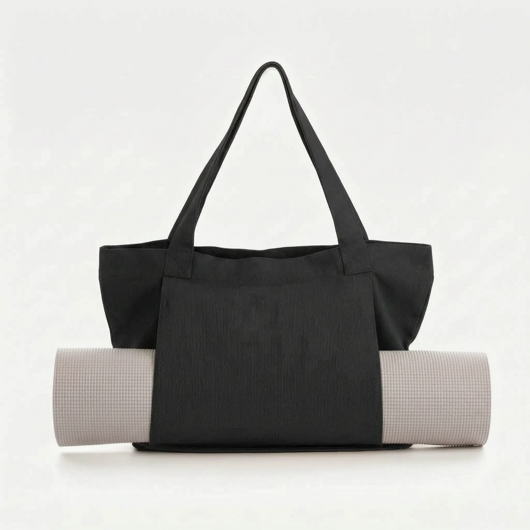 Detail view of a large canvas yoga mat tote bag pocket, showing space for water bottle & personal items.
