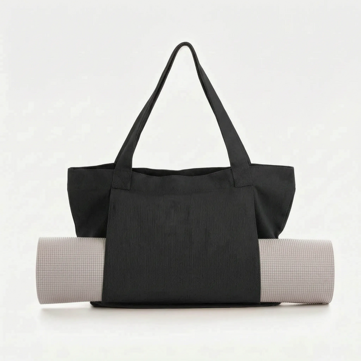Detail view of a large canvas yoga mat tote bag pocket, showing space for water bottle & personal items.