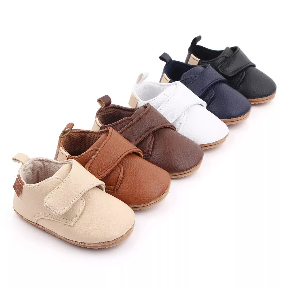 Classic white leather baby anti-slip first walker shoes on wooden floor, clean design