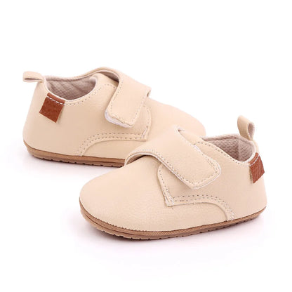 Infant feet wearing classic black leather anti-slip baby first walker shoes, secure fit