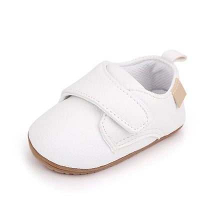 Adorable baby wearing classic red leather anti-slip first walker shoes, playing indoors