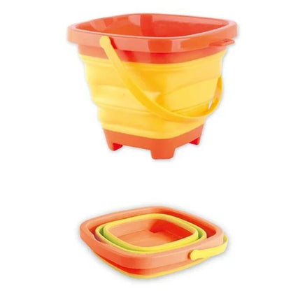 Child playing with a yellow collapsible silicone beach bucket on sandy beach, durable outdoor toy