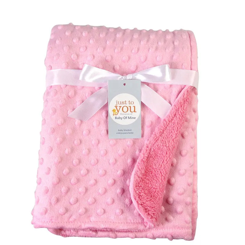 Multi-use double layer cotton baby blanket, shown draped over a crib rail, an ideal baby gift.