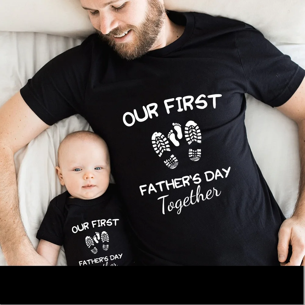 Flat lay of 'First Father's Day' matching t-shirt for dad and baby romper, print clothing
