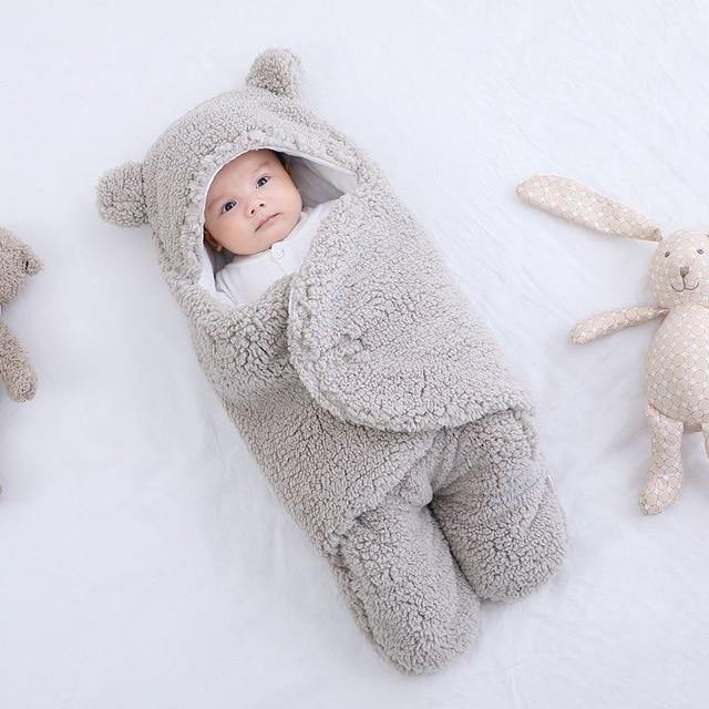 Infant sleep swaddle blanket with adorable bear ears, made from plush fleece material.