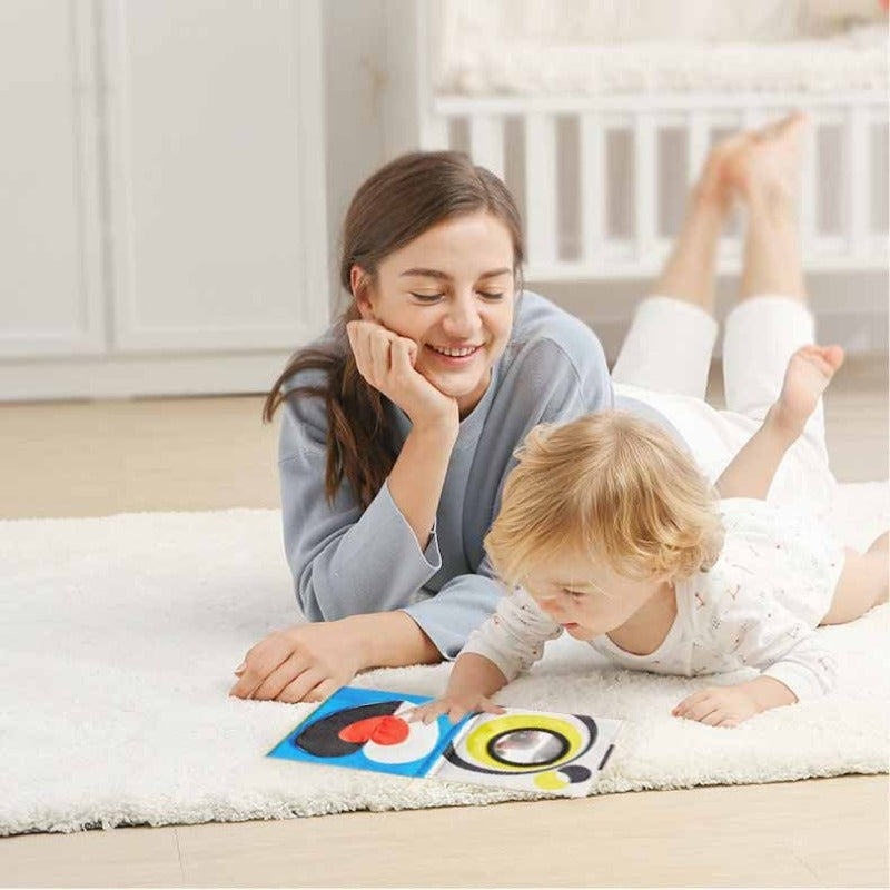 Toddler holding a soft cloth activity book with colorful 3D elements, great for infant learning