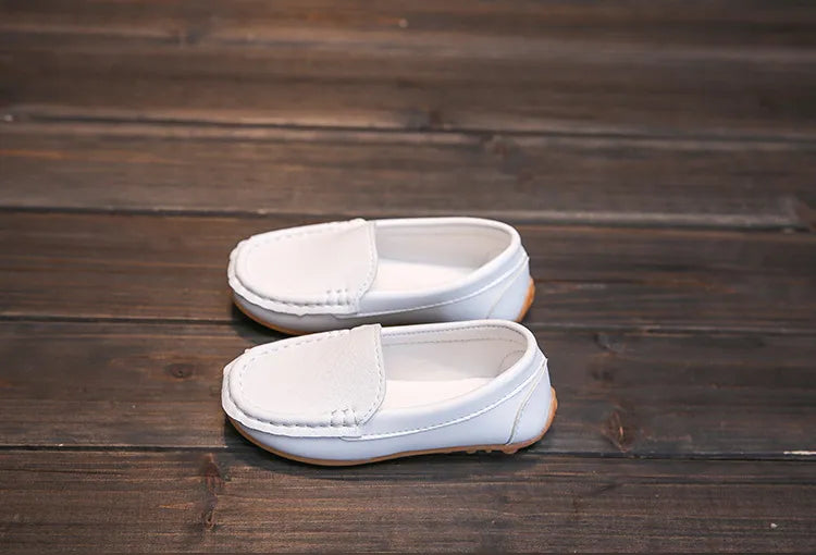 A child tying their shoelaces on unisex breathable slip-on loafers. Kids shoes, anti-slip.