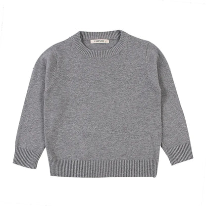 Child playing outdoors wearing a warm unisex cable knit pullover
