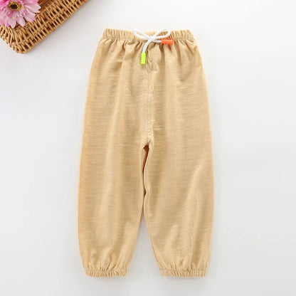 Folded stack of unisex kids cotton breathable summer pants in various colors, sustainable fashion