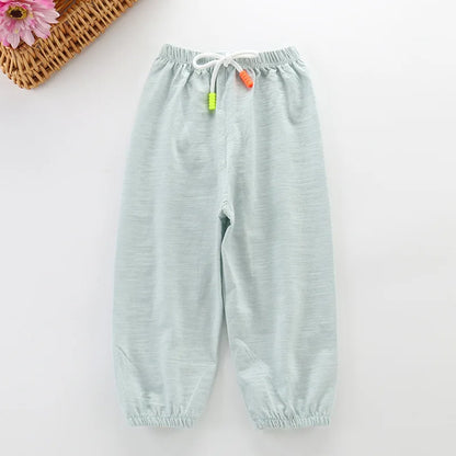 Unisex baby clothing cotton blend summer pants, light orange, on natural wood background, soft fabric