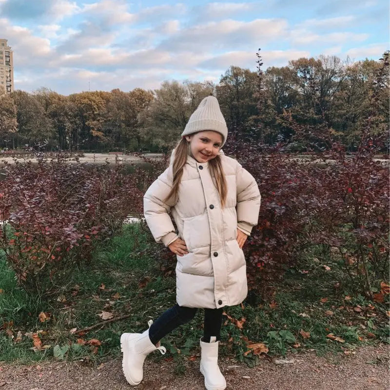 Unisex kids' long winter jacket, hooded, padded, shown on a child playing in snow.