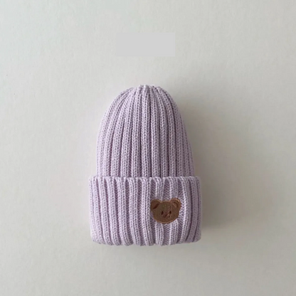 Knitted kids beanie hat in a soft fabric, adorned with a delightful bear embroidery, keeps heads warm.