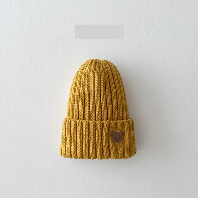 Snug-fitting knitted beanie hat for kids, with a cute bear embroidery, providing warmth and charm.