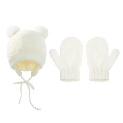 Child wearing a knitted pompom hat and gloves set, ready for cold weather outdoor play