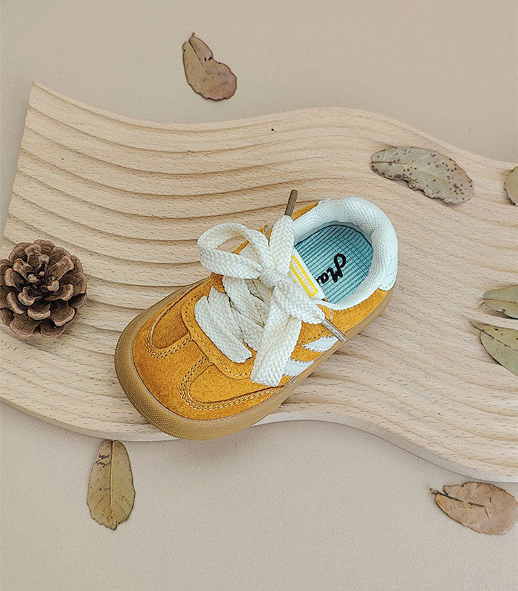 Toddler on playground wearing unisex laced sneakers, showing flexible sole in action.