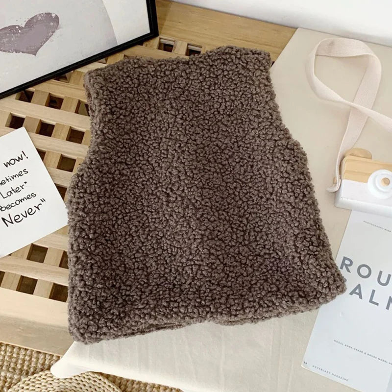 Hand touching the soft lining of a lamb wool vest, extra warmth for baby outerwear