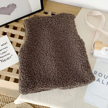 Hand touching the soft lining of a lamb wool vest, extra warmth for baby outerwear