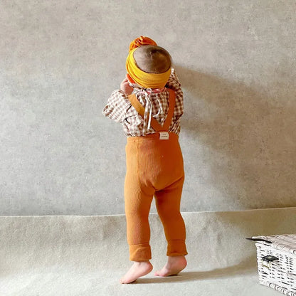Close-up of the adjustable suspenders on kids' cotton leggings, showing button details