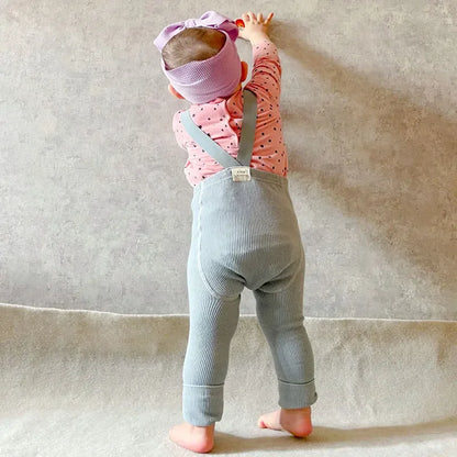 Child playing while wearing durable cotton leggings with suspenders, ensuring comfort
