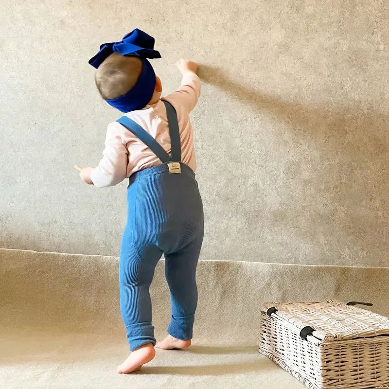 Front view of black soft cotton baby leggings with classic suspenders, unisex design