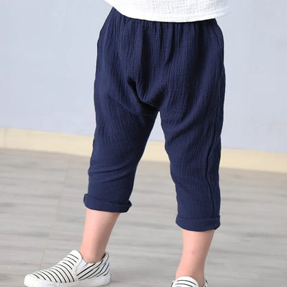 Stack of folded unisex kids' summer linen blend solid color pants in various colors