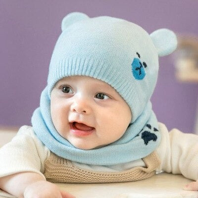 Cute toddler boy wearing a blue knitted beanie cap and matching scarf, smiling at camera