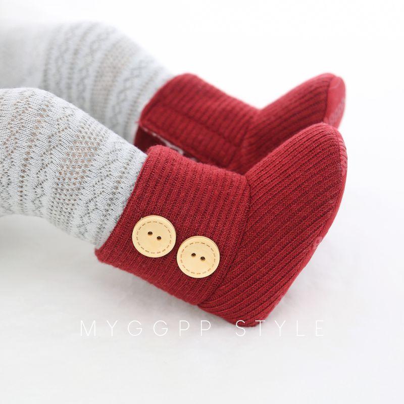 Close-up of a grey knitted baby boot, showing soft fabric and secure velcro fastening.