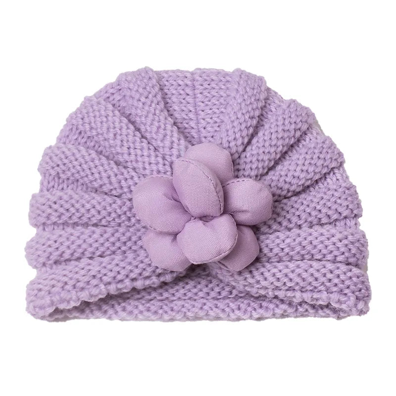 Baby's sleepy face in a soft knitted candy color baby hat, comforting winter accessory