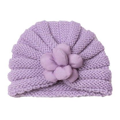 Baby's sleepy face in a soft knitted candy color baby hat, comforting winter accessory