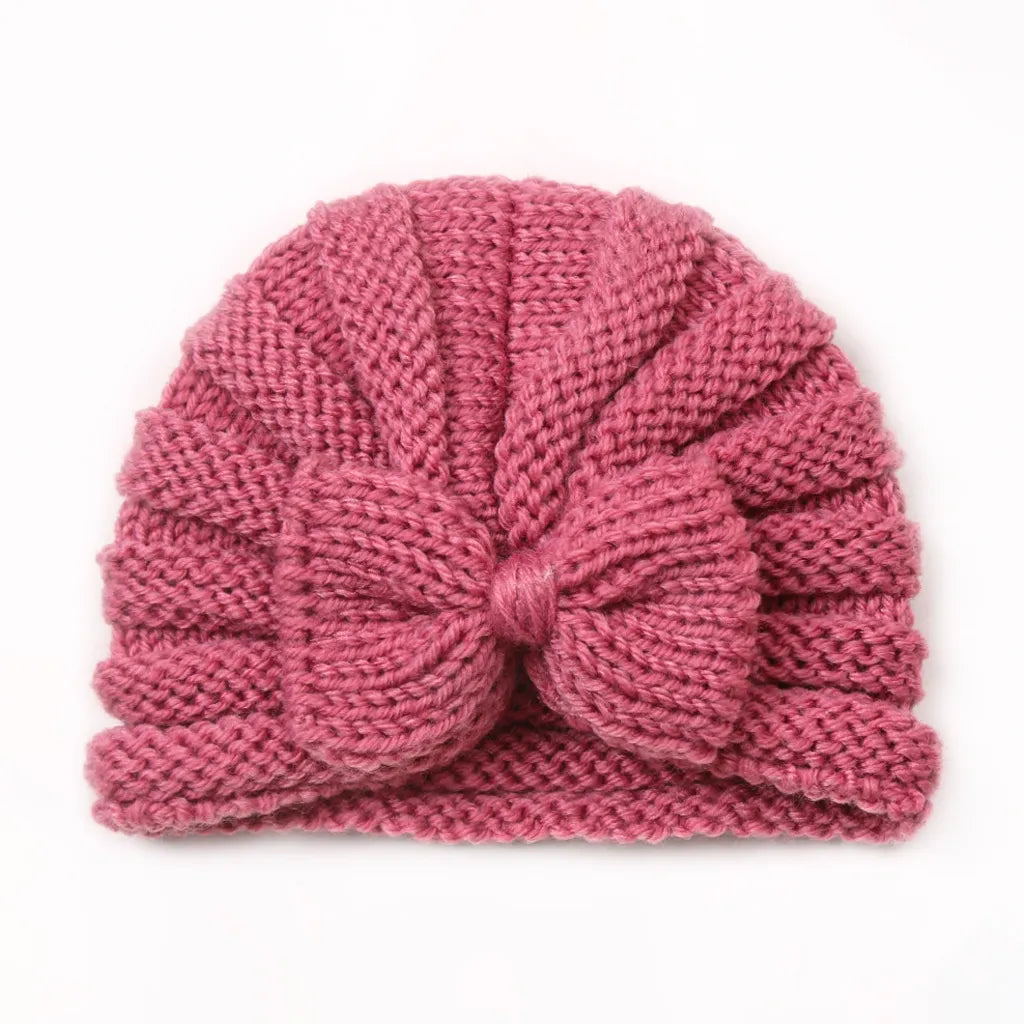 Knitted baby hat in bright candy colors on a hanger, ready for winter adventures