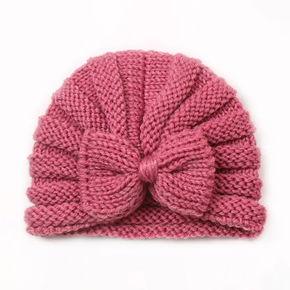 Knitted baby hat in bright candy colors on a hanger, ready for winter adventures