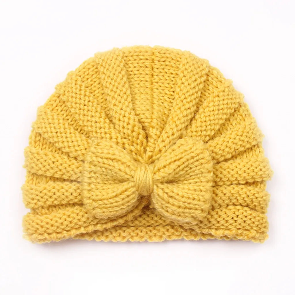 Infant happily sitting with a snugly fitted knitted candy color beanie, winter comfort