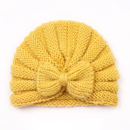 Infant happily sitting with a snugly fitted knitted candy color beanie, winter comfort