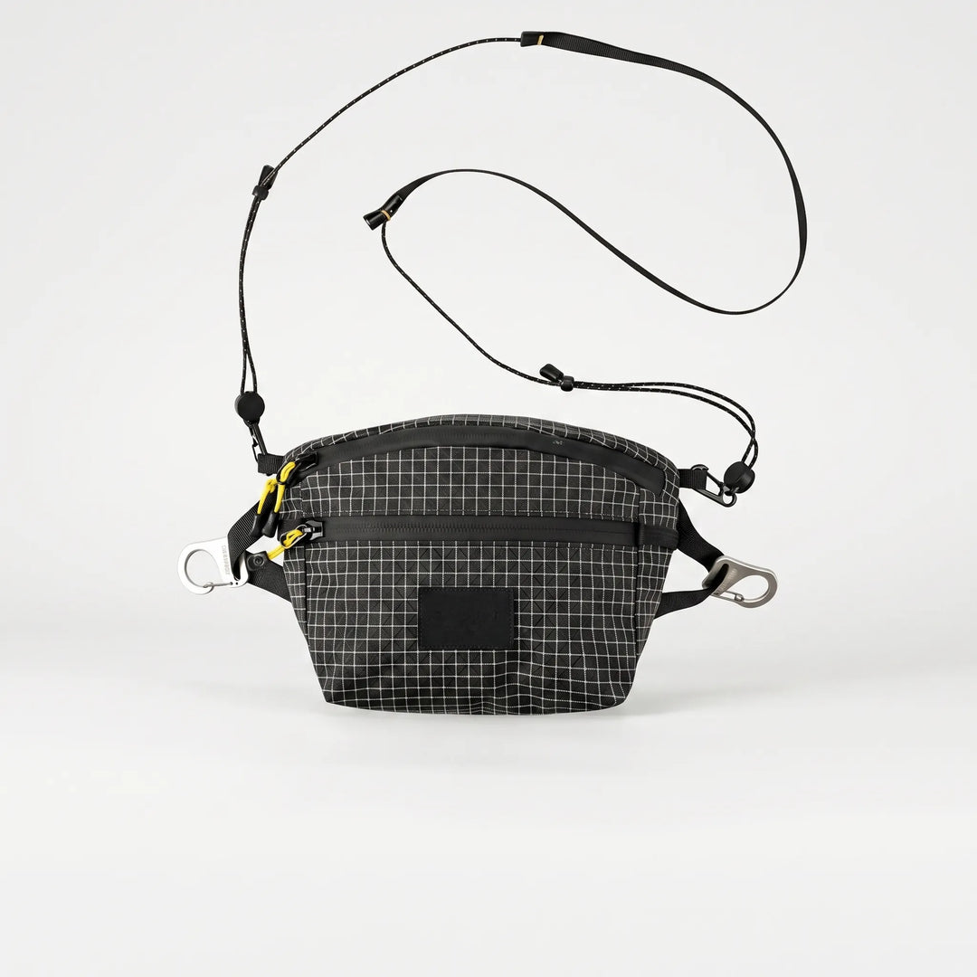 Person wearing a unisex grid crossbody chest bag, ideal for outdoor adventures & carrying travel essentials.