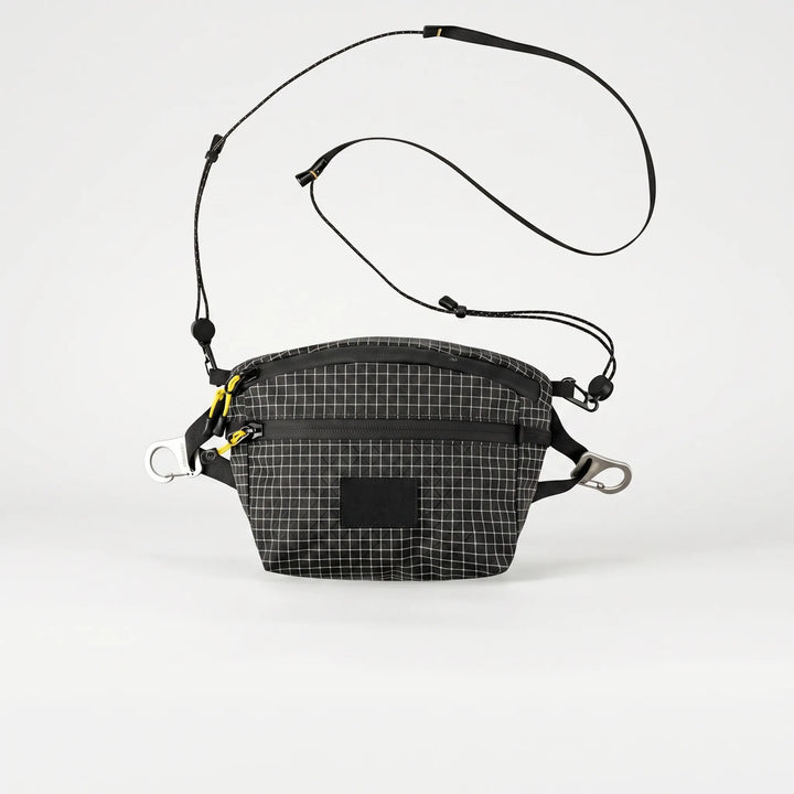 Person wearing a unisex grid crossbody chest bag, ideal for outdoor adventures & carrying travel essentials.