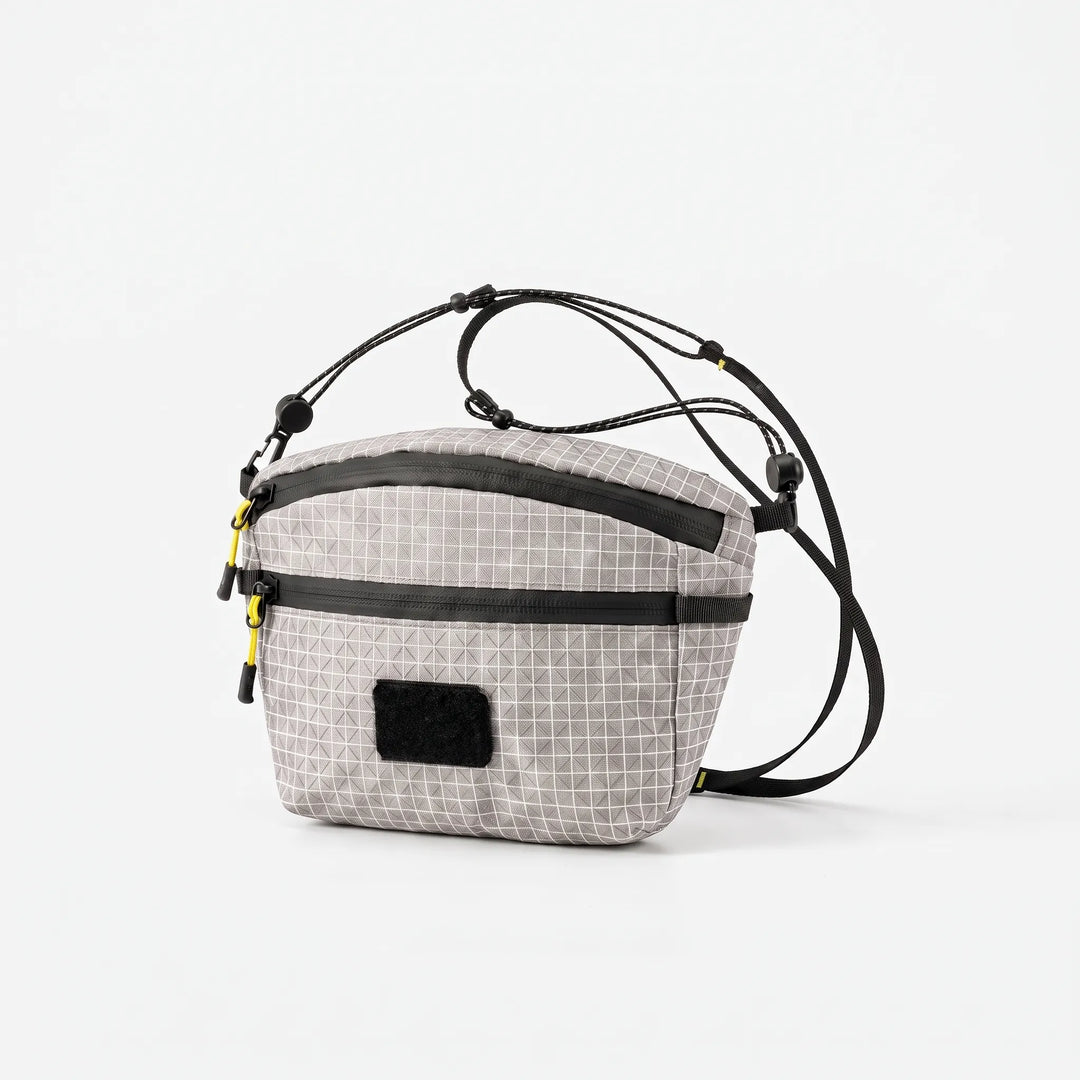 Back view of a black unisex grid chest bag with adjustable strap, suitable for comfortable crossbody wear.