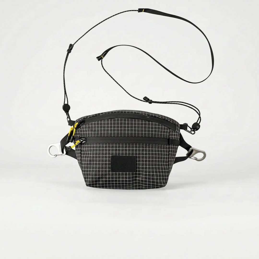 Unisex grid adventure bag worn during a hike, a practical crossbody sling for outdoor gear & essentials.