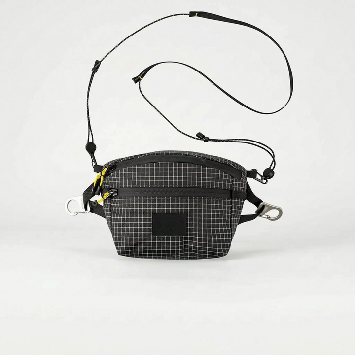 Unisex grid adventure bag worn during a hike, a practical crossbody sling for outdoor gear & essentials.