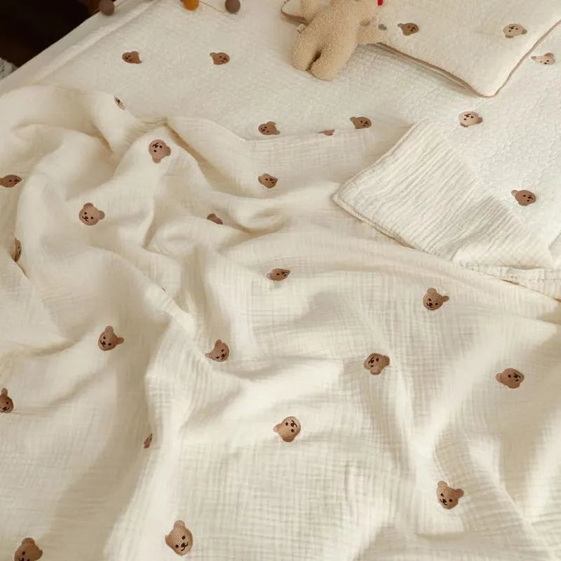 Soft white cotton baby blanket, unisex, featuring cute embroidered bear, ideal for infant bedding and swaddling.
