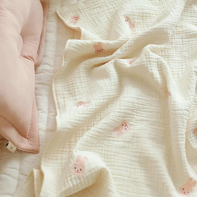 Close-up texture of a soft cotton baby blanket illustrating an embroidered dinosaur, designed for infant comfort.