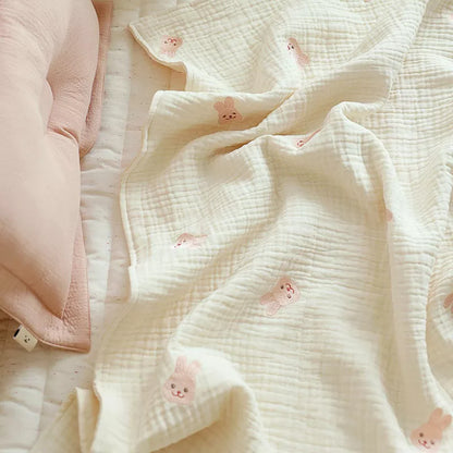 Close-up texture of a soft cotton baby blanket illustrating an embroidered dinosaur, designed for infant comfort.