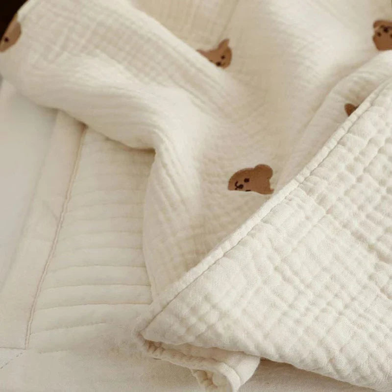 Folded newborn cotton blanket with charming embroidered bunny, suitable for nursery decor and summer use.
