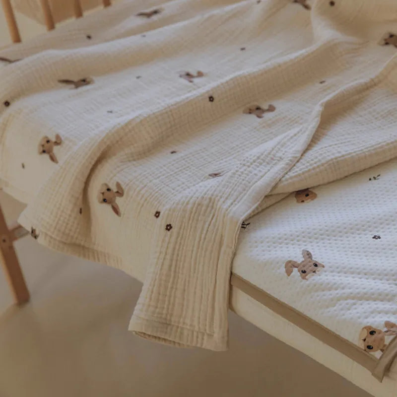 Stacked cotton baby blankets, pastel colors, each with unique animal embroidery, for versatile nursery bedding.