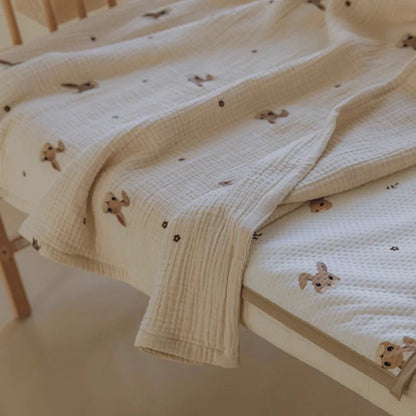 Stacked cotton baby blankets, pastel colors, each with unique animal embroidery, for versatile nursery bedding.