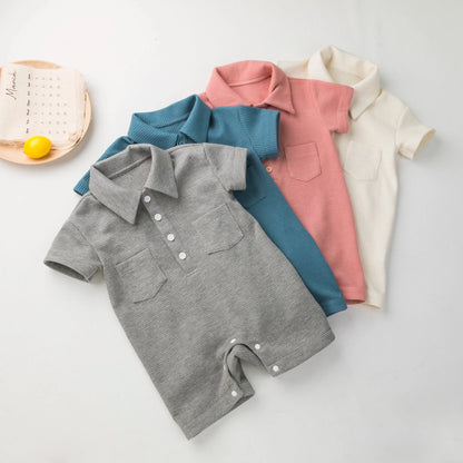 Display of various colored short sleeve baby jumpsuits on a rack.