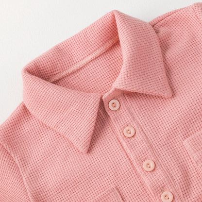 Close-up of a pink short sleeve cotton baby jumpsuit, soft fabric texture.