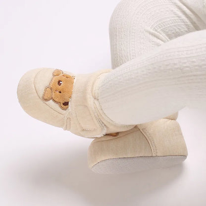 Baby's feet in soft plush bear booties, warm first walker shoes for winter