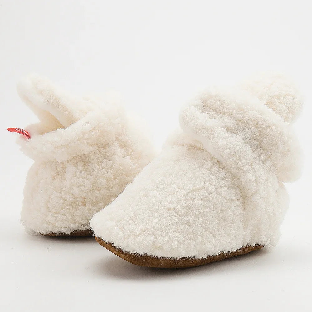 Close-up of fluffy baby booties for infants, soft cotton material, unisex design, anti-slip soles.