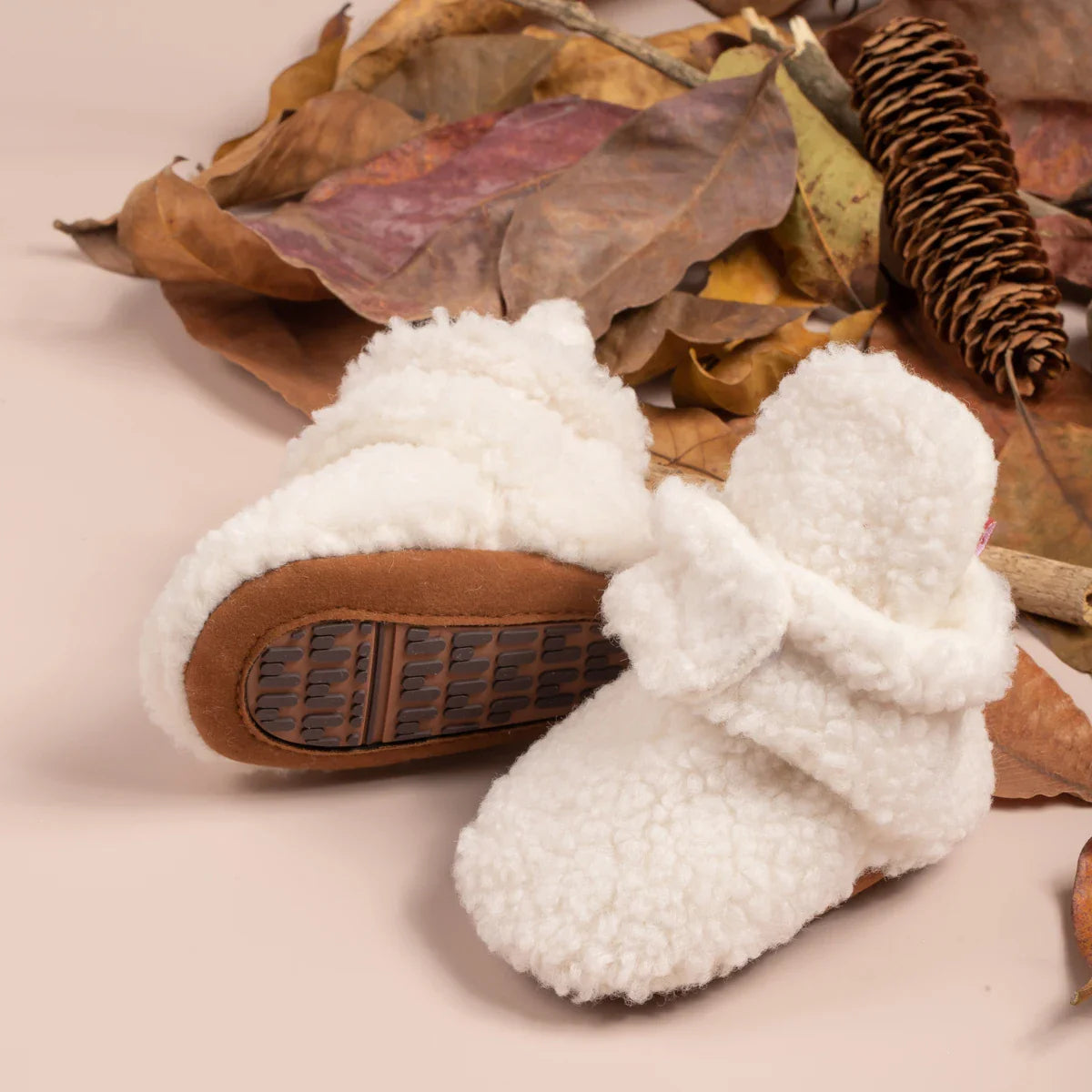 Detail of the anti-slip sole on unisex soft fluff baby booties, safety for infant first steps.
