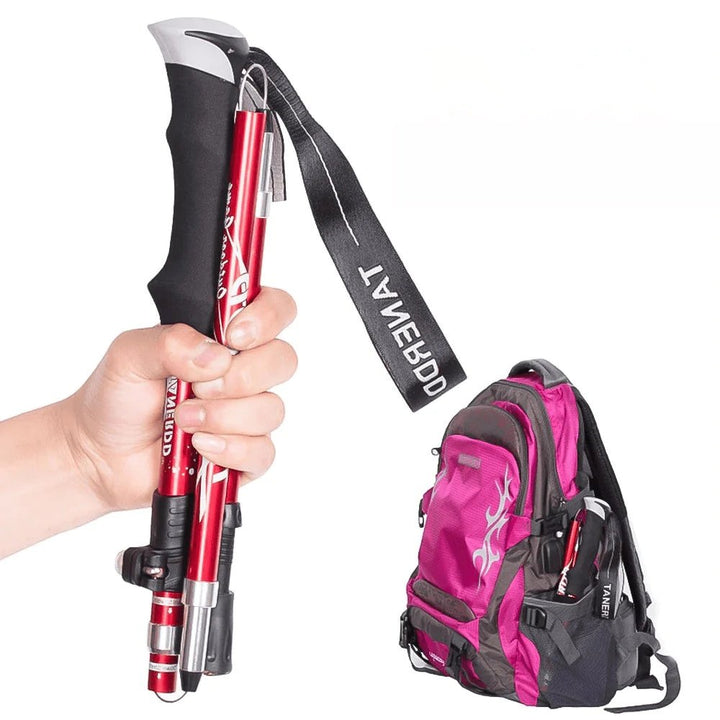 Red adjustable telescopic hiking stick, ideal for stability on rugged trails. Essential trekking & camping gear.